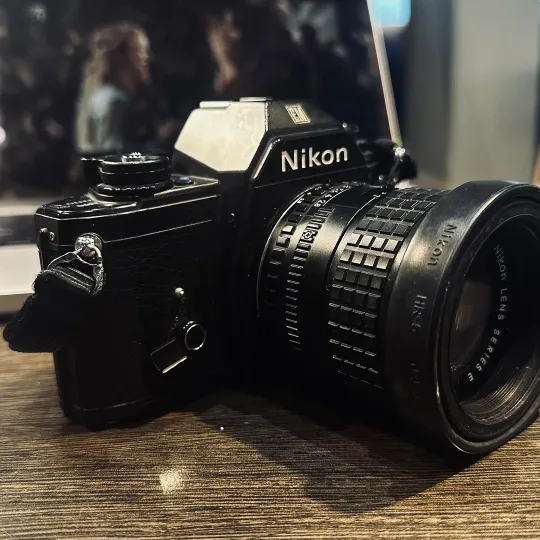 Black Nikon film camera with a large lens, on a wooden table