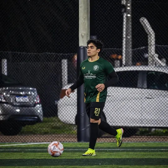 Moiséz on a football pitch at night, in a green kit with the number 21